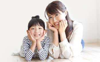 横に並んで頬杖をついてる笑顔の親子